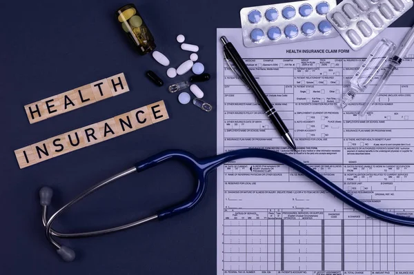 Health insurance form claim with stethoscope, pills and injection on table. Medical insurance, health risk, pay for the healthcare concept.