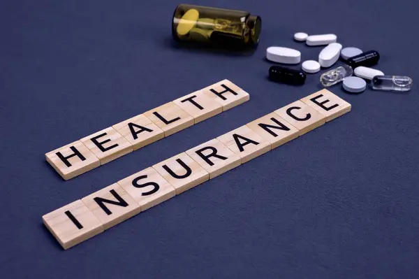 Health insurance text with pills on gray background. Medical insurance, health risk, pay for the healthcare concept.