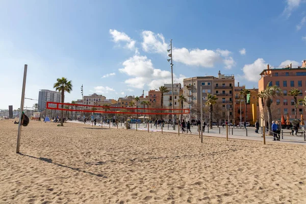 stock image Barcelona, Spain - FEB 10, 2022: Buildings and people along the Barceloneta beach in Ciutat Vella district of Barcelona, the Mediterranean coast, Spain.