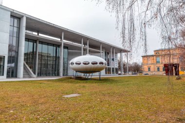 Munich, Germany - DEC 23, 2021: A prototype of a Futuro house from 1968 next to the Pinakothek der Moderne.UFO shaped futuristic design by Finnish architect Matti Suuronen. clipart