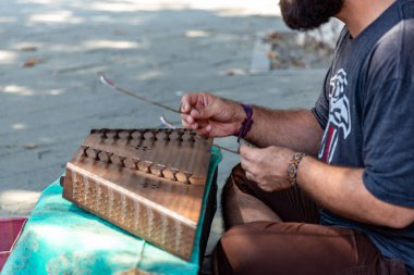 Tbilisi, Georgia - 14 AUG, 2024: Young Iranian musician playing santur, a traditional Persian musical instrument and singing in the street in Tbilisi. clipart