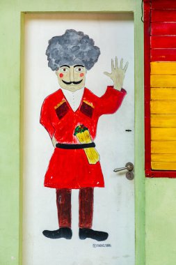 Tbilisi, Georgia - 23 JUNE, 2024: Small doner restaurant Ra Shaurma with a hand painted male figure in traditional Georgian chokha. clipart