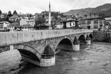 Sarajevo - Bosnia and Herzegovina - 11 FEB 2024: Sehir Kayhasi or Seher Cehaya stone bridge built during the Ottoman period over Miljacka River in Sarajevo. clipart