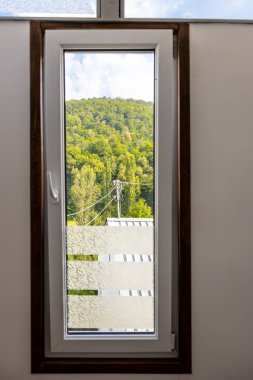 Ermenistan 'ın Dilijan şehrinde güneşli bir yaz gününde kapalı pencereden aşırı gelişmiş dağın manzarası