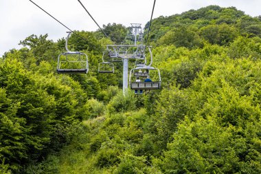 cable car lifts on top of mount in Tsaghkadzor town, Armenia on summer cloudy day clipart