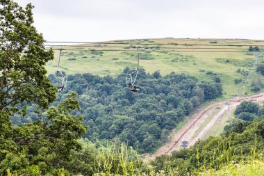 ropeway over mountain road near Tsaghkadzor town, Armenia on summer cloudy day clipart