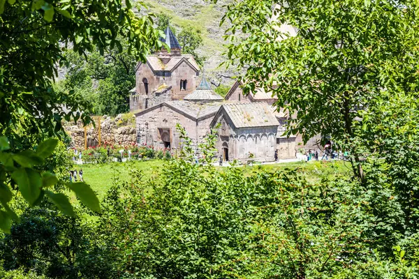 stock image Gosh, Armenia - July 6, 2024: view of Goshavank monastery through green trees, Armenia on sunny summer day from Saint Gevorg church