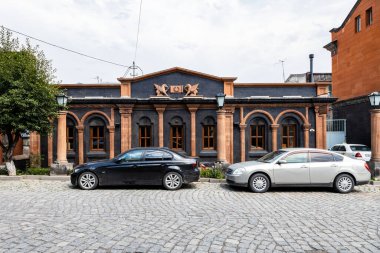 Gyumri, Ermenistan - 20 Temmuz 2024: Bulutlu bir yaz gününde Gyumri şehrinde geleneksel tarzdaki siyah ve kırmızı Tuff 'tan yapılmış modern bina