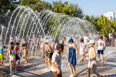 Erivan, Ermenistan - 10 Ağustos 2024: Güneşli yaz gününde Erivan 2800. yıl dönümü parkında kemer çeşmesindeki çocuklar