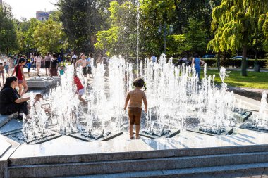 Erivan, Ermenistan - 10 Ağustos 2024: Güneşli yaz gününde Erivan 2800. yıldönümü parkındaki çeşme havuzunda çocuklar