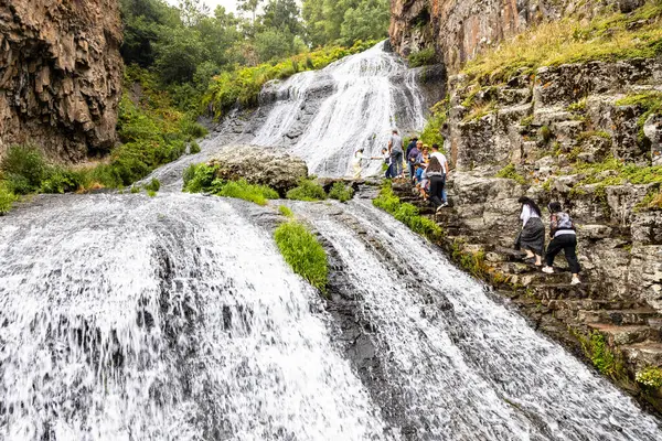 Jermuk, Ermenistan - 3 Ağustos 2024: Turistler yağmurlu yaz günlerinde Arpa nehri vadisindeki Jermuk Şelalesine yürür