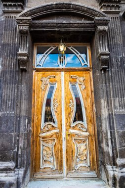 Yazın alacakaranlıkta Ermenistan 'ın Gyumri şehrindeki Abovyan Caddesi' ndeki siyah Tuff 'tan yapılmış otnamental ahşap ev kapısı.