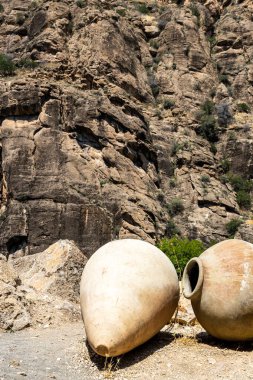 old kvevri wine vessels near rock in Areni village in Vayots Dzor Provinces, Armenia on sunny summer day clipart