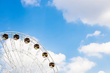 Güneşli yaz gününde Erivan şehrindeki Zafer Parkı 'nda beyaz bulutlu mavi gökyüzü ve dönme dolap.