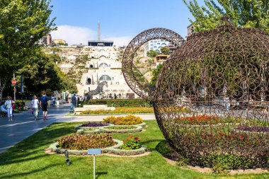 Erivan, Ermenistan - 1 Ekim 2023: Güneşli sonbahar gününde Erivan şehrinde heykellerle süslenmiş Cascade merdivenleri yakınındaki Tamanyan caddesi yeşil bulvarı