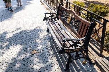 Erivan, Ermenistan - 1 Ekim 2023: Erivan şehrinde sonbaharda sokak arması olan kentsel ahşap bank. Erivan Ermenistan 'ın başkentidir.