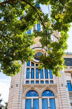 Batumi, Gürcistan - 15 Eylül 2023: Gürcistan Merkez Bankası 'nın arka planında güneşli bir sonbahar gününde yeşil yapraklar ve astronomik saat