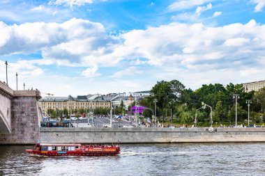 Moscow, Russia - July 31, 2022: view of Moskva river with sightseeing boat near Bolshoy Moskvoretsky Bridge and Moskvoretskaya Embankment from Raushskaya embankment in summer evening clipart