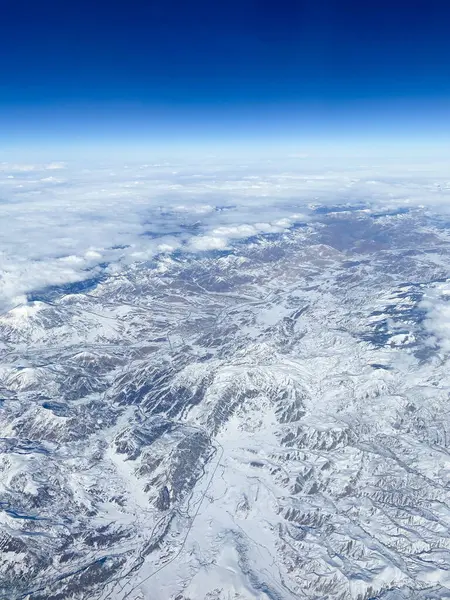 aerial view of snow-covered mountains and valleys of Caucasus from airplane