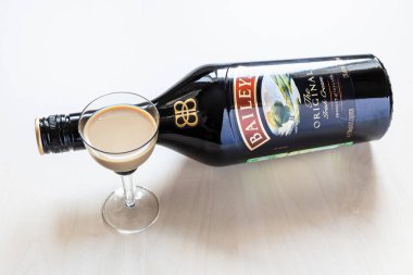 Moskova, Rusya - 2 Ağustos 2022: İrlanda 'da Diageo tarafından İrlanda' da üretilen İrlanda kremalı Baileys likörünün soluk masa ve şarap bardağına (şişe üzerine odaklanma) bakınız)