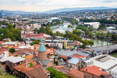 Tiflis, Gürcistan - 23 Eylül 2023: Bulutlu sonbahar akşamında Narikala kalesinden St. George Church ve Rike parkı ile Tiflis şehri manzarası