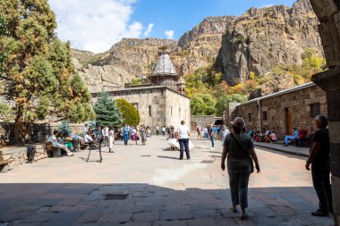 Goght, Ermenistan - 30 Eylül 2023: Güneşli sonbahar gününde Yukarı Azat Vadisi 'ndeki Geghard Manastırı' nın avlusundaki insanlar. Geghard UNESCO Dünya Mirası Listesi