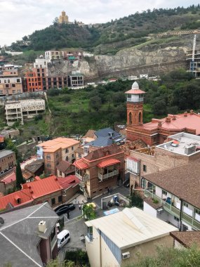 Tiflis, Gürcistan - 23 Eylül 2023: Bulutlu bir sonbahar gününde Tiflis-Mta Dağı 'ndaki konut evleri ve Juma camii minaresi ve Favorsky Spaso-Preobrazhensky Manastırı