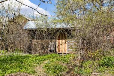 Güneşli bahar gününde köyün arka bahçesinde kapalı kapılı ahşap ahır manzarası