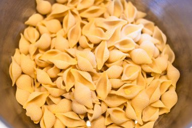 top view of portion of uncooked conchiglie rigate pasta in saucepan clipart