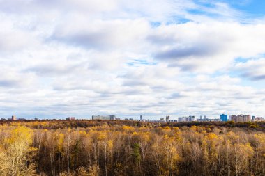 cloudy sky over forest and city on horizon on sunny autumn day clipart