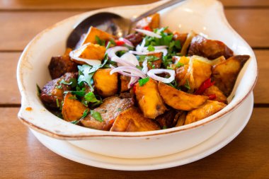 travel to Georgia - portion of Ojakhuri (Georgian dish, fried meat with potatoes) in bowl on wooden table in local cafe in Batumi city clipart