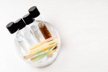 above view of several test tubes with liquids and solutions and litmus papers in glass bowl on light desk with copyspace clipart