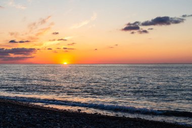 Gürcistan 'a seyahat - sonbahar akşamı Batumi' deki çakıl taşı plajından ufkun üzerinde batan güneş manzarası