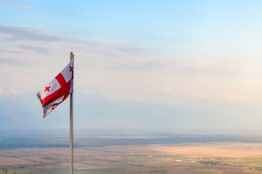 travel to Georgia - georgian flag over Alazan valley in Kakheti region in Georgia in autumn twilight clipart