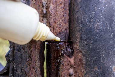 Paslı kapı menteşesi plastikten çıkan yağla kaplanıyor.