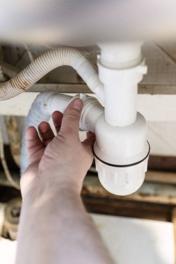 Tesisatçının eli, eski plastik boruları söküp köy evinin mutfağını kapatıyor.