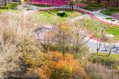 Güneşli bir sonbahar gününde renkli şehir parkındaki oyun parkının manzarasının üstünde