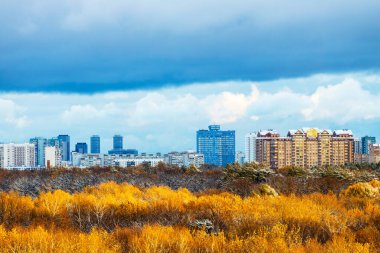 Sonbahar akşamı evlerin ve şehir parkının üzerinde koyu mavi kar bulutu