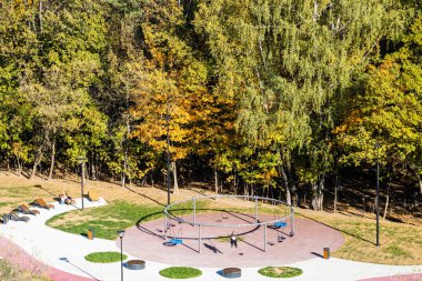 Güneşli sonbahar gününde şehir parkında salıncaklı oyun parkı manzarasının üstünde.