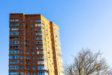 Tuğla gökdelenli apartman dairesi sonbahar akşamında günbatımı güneşi ve mavi gökyüzü ile aydınlanıyor.