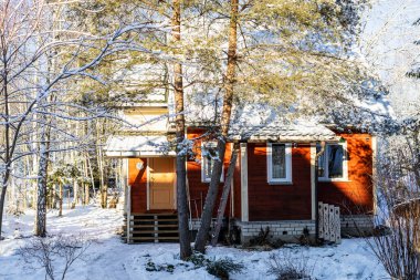 Kış günü köyün karlı bahçesinde küçük bir ahşap kulübe.