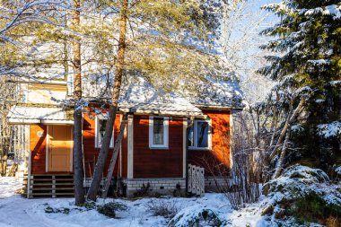 Kış günü köyün karlı bahçesinde küçük ahşap bir kır evi.