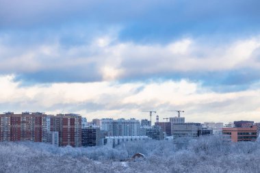Kar bulutları modern apartman binalarının ve şehir parkının üzerinde kış akşamının alacakaranlığında