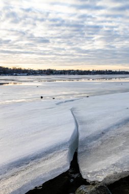 iced blocks on riverbank of frozen river in Kostroma city in winter evening twilight