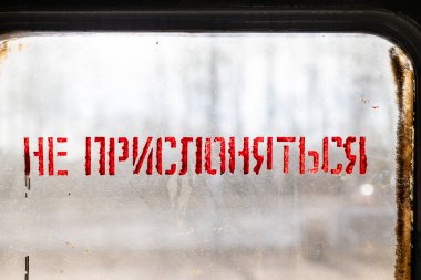 Kırmızı Boya Kapılara yaslanmayın Rusça metin cam pencere üzerinde güneşli bahar akşamlarında yerel tren taşıma.
