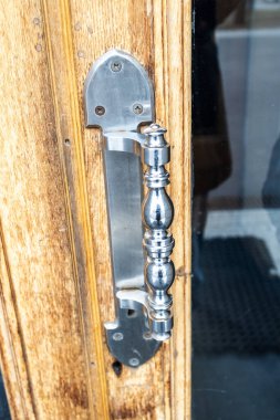 Eski açık ahşap kapı koluna cilalanmış çelik kapı kolu. Kapatın.