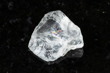 Madagaskar yakınlarındaki siyah granit arka planda çiğ, renksiz beril minerali örneği.