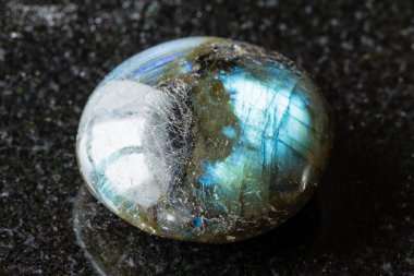 Madagaskar yakınlarında siyah granit arka planda cilalanmış labradorit minerali örneği