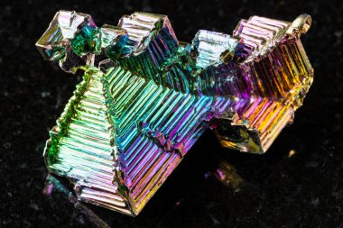 Siyah granit arka planda çiğ yetişmiş bizmut kristalleri minerali örneği yakın plan