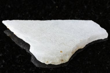 Siyah granit arka planda cilalanmış beyaz nefrit minerali örneği. Çin 'den yakın plan.